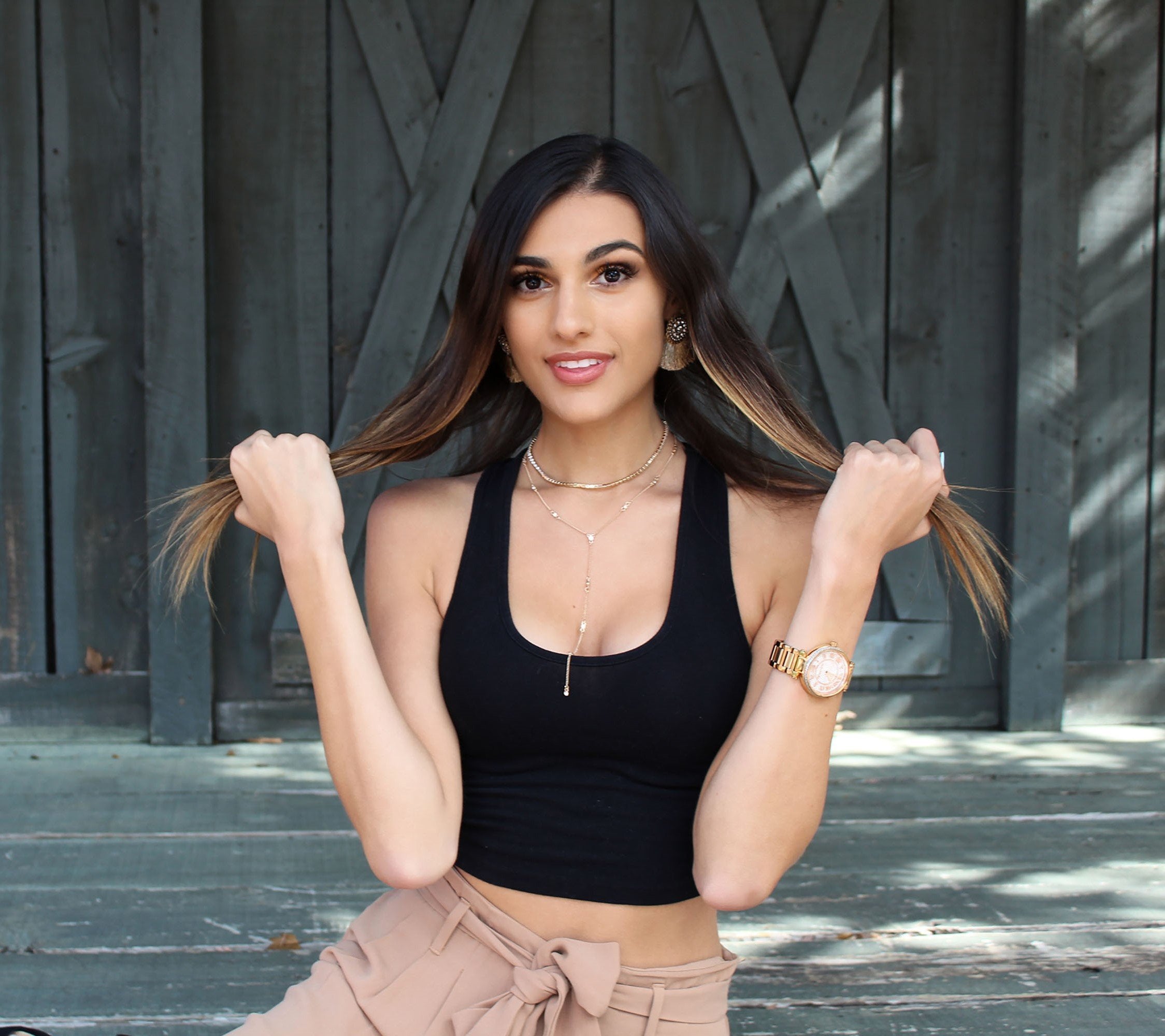 A women holding her hair on each side and wearing Jewelry