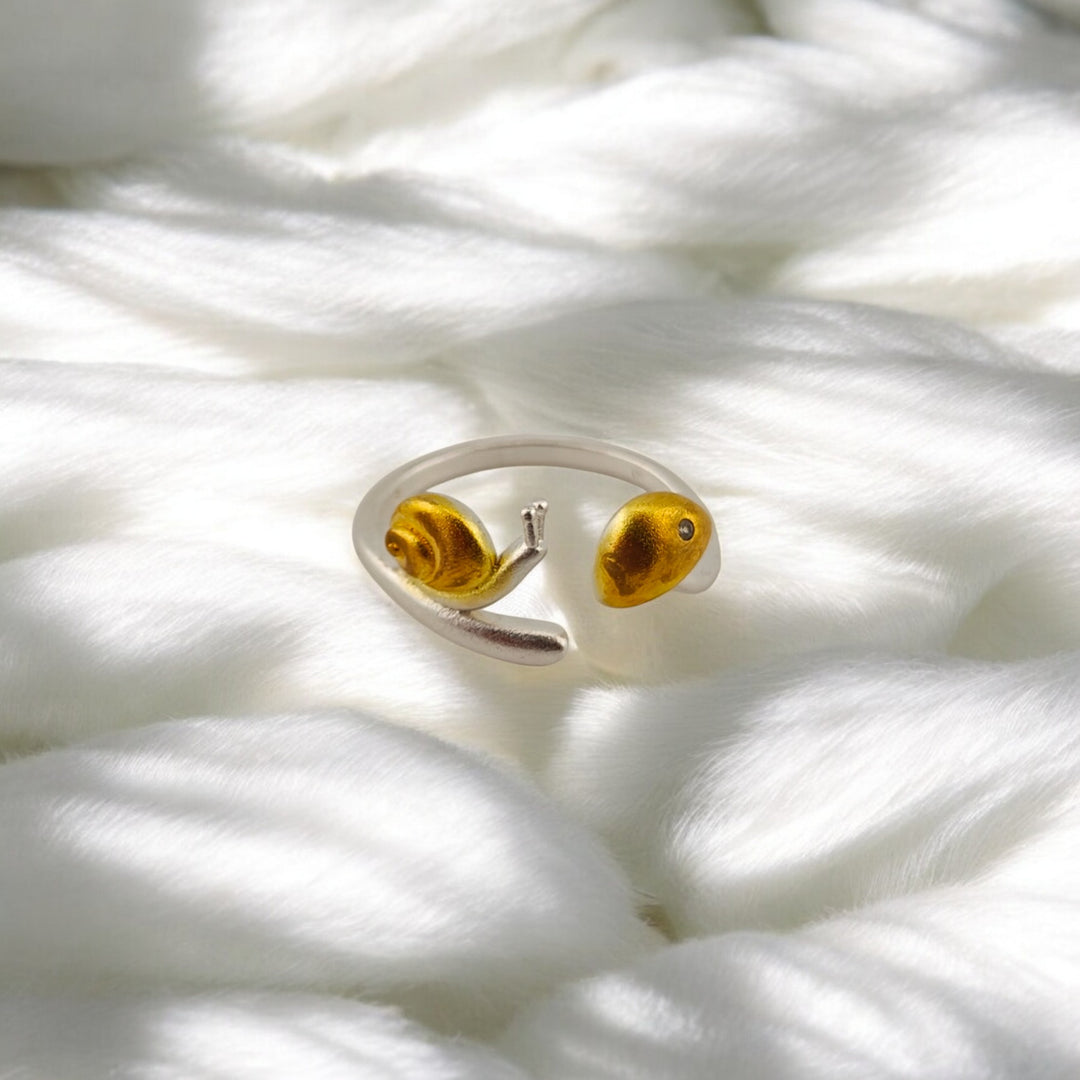 Close-up of golden snail design on silver open ring
