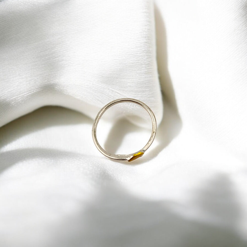 Top view of silver ring with yellow raindrop and cloud on white fabric