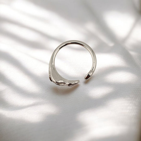 Top view of botanical silver ring with single calla bloom and swirl end