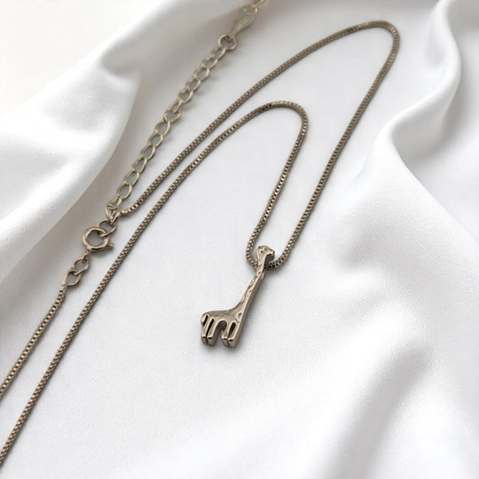 Silver necklace with minimalist giraffe pendant on white satin