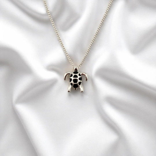 Turtle pendant centered on soft white fabric