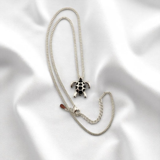 Turtle necklace displayed in a diagonal layout on satin