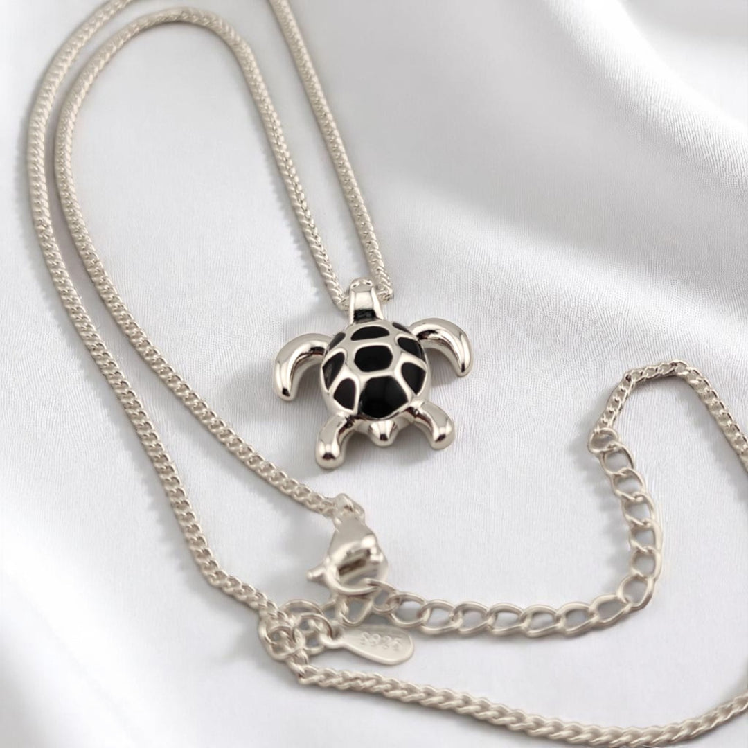 Elegant turtle pendant lying flat with open chain around