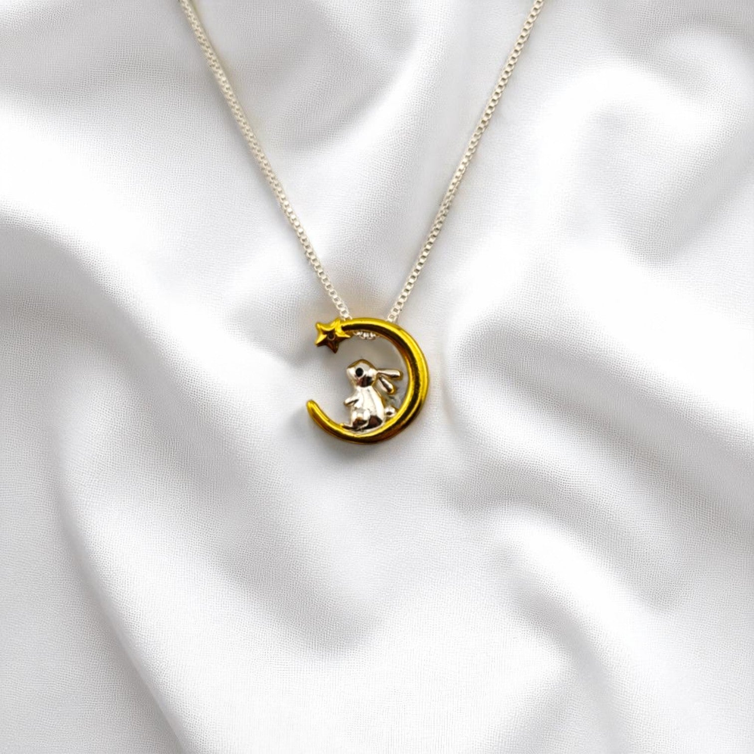 Moon bunny pendant necklace resting on soft white fabric – RossJewelrys