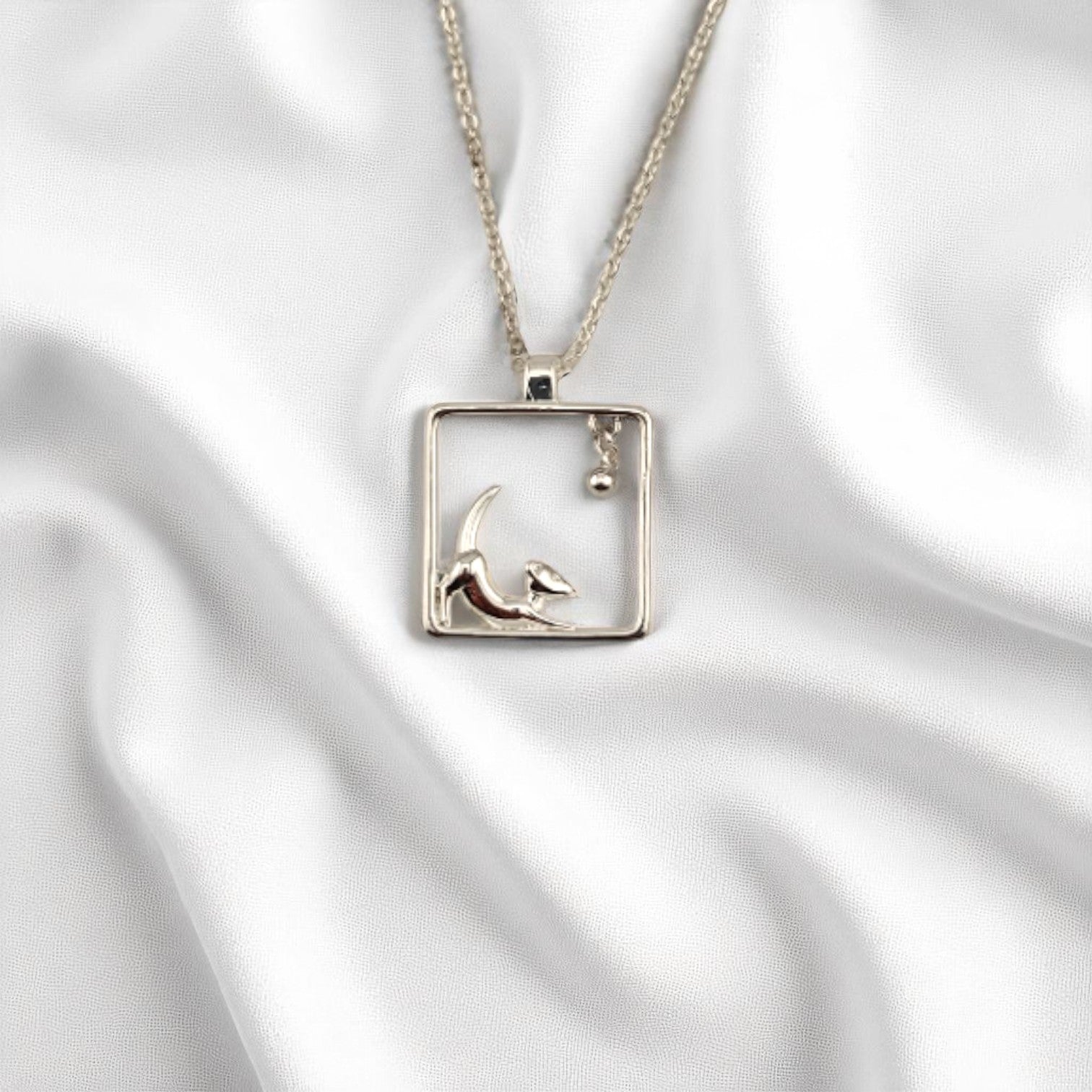 Playful puppy charm necklace with silver chain on white fabric