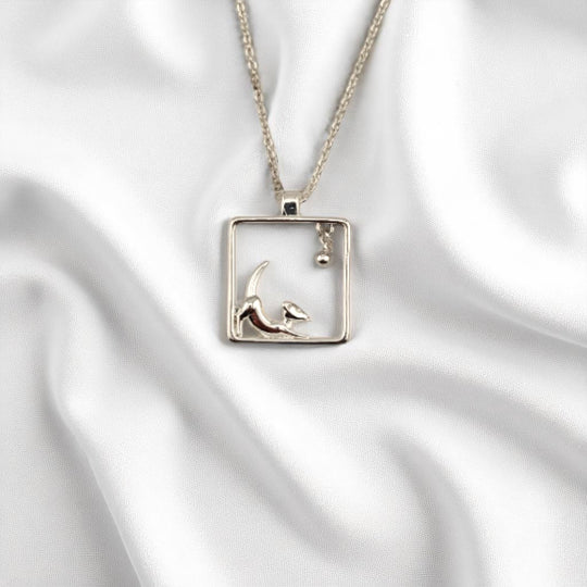 Playful puppy charm necklace with silver chain on white fabric
