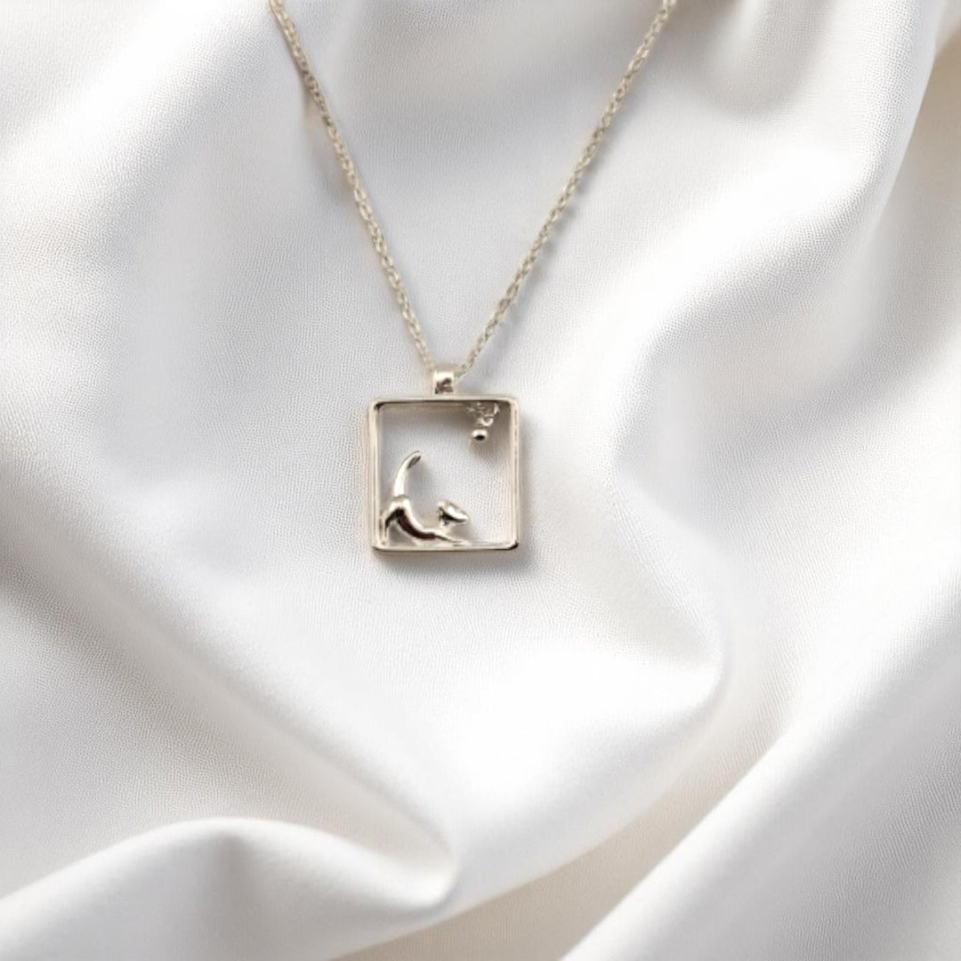 Silver necklace with dog and ball inside square frame pendant