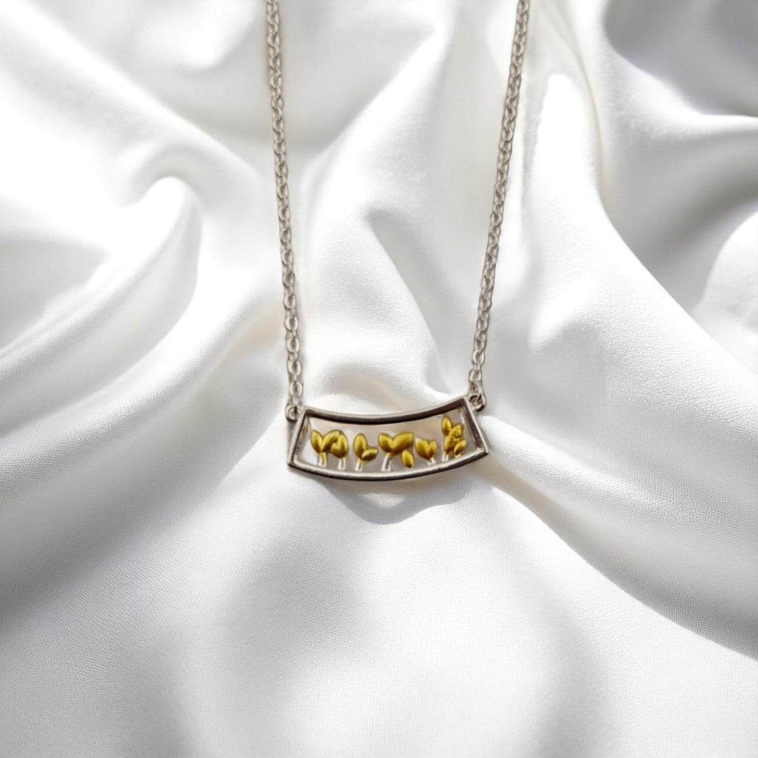 Silver necklace with yellow leaf sprouts in curved frame pendant