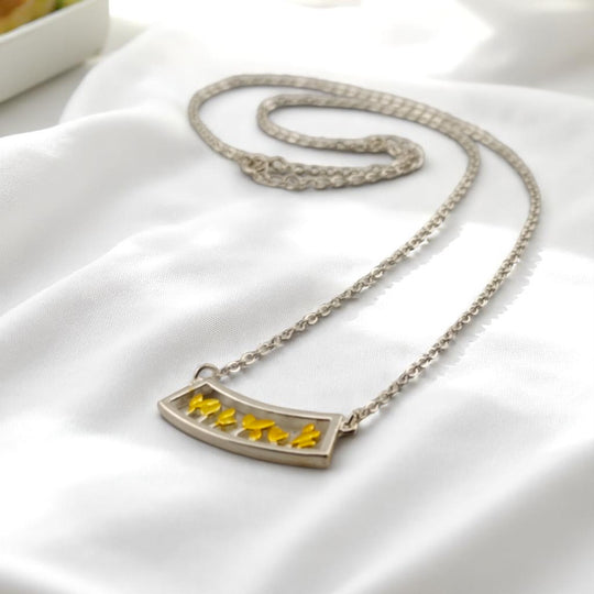 Yellow enamel leaf charm necklace displayed on white background