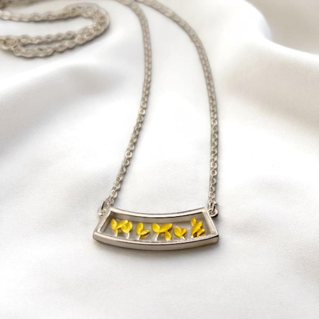 Leaf sprout pendant necklace with silver chain on satin fabric