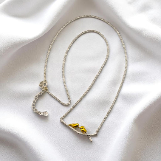 Close-up of lovebird pendant necklace on white satin background