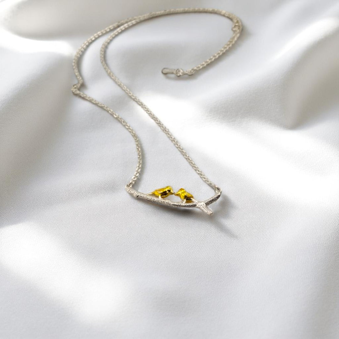 Romantic bird charm necklace resting on smooth white fabric