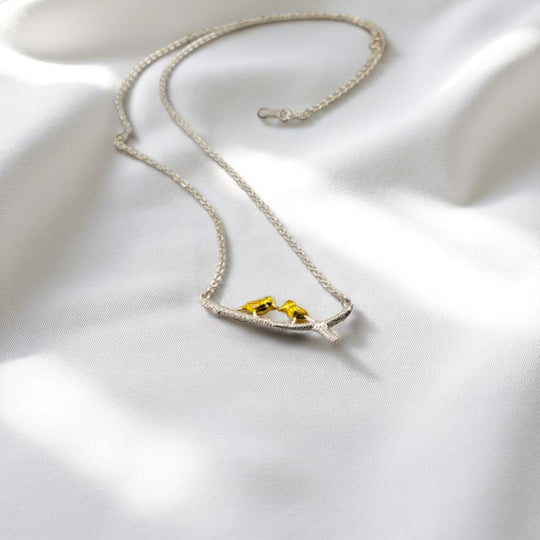 Romantic bird charm necklace resting on smooth white fabric