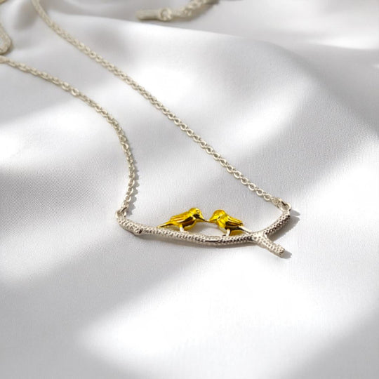 Silver chain necklace with enamel birds on branch in sunlight