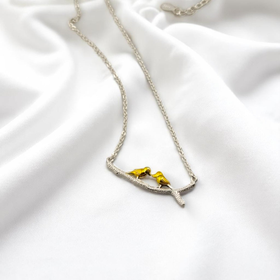 Silver necklace with two yellow birds sitting on a branch pendant