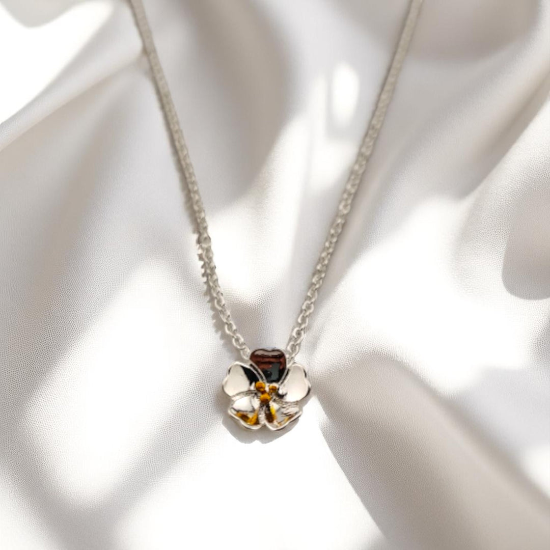 Silver necklace and white pansy flower pendant on white fabric