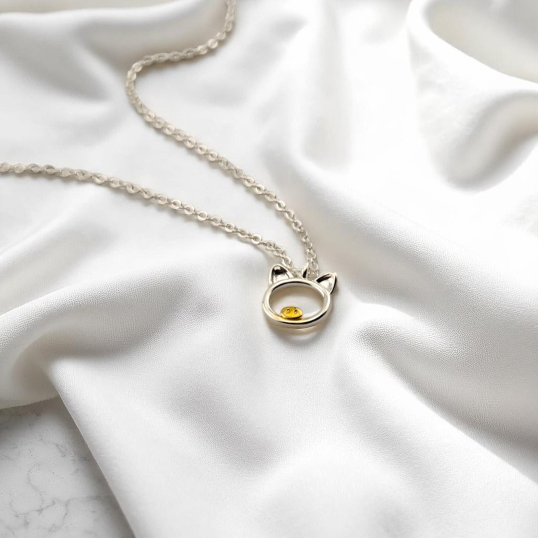 Angled view of silver pig necklace highlighting the shiny finish