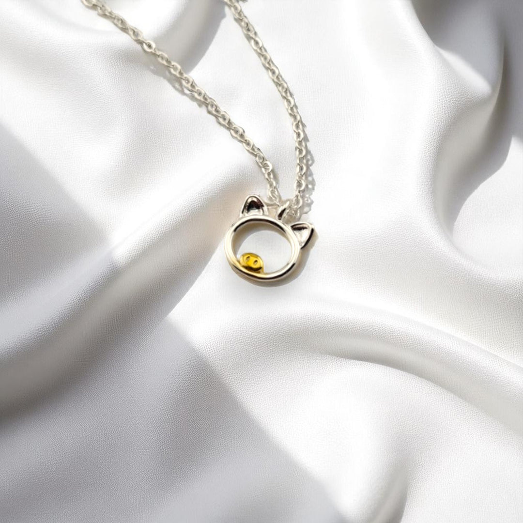 Silver pig pendant necklace displayed on white satin fabric