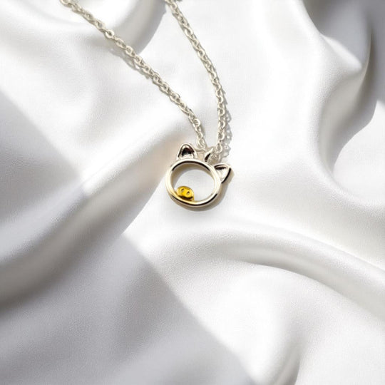 Silver pig pendant necklace displayed on white satin fabric