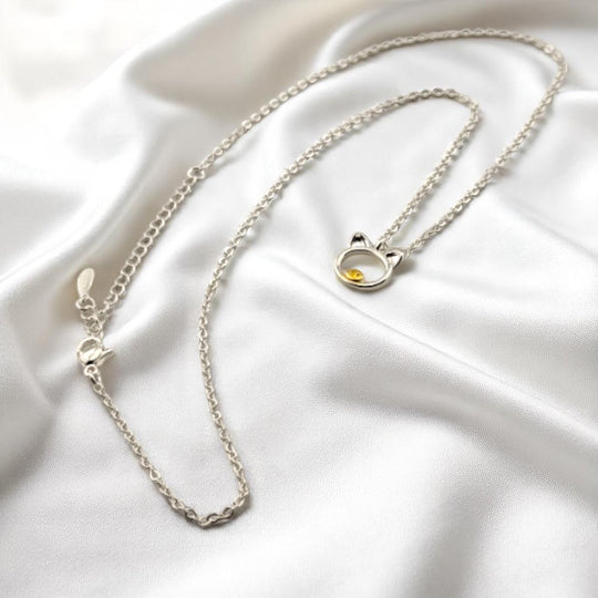 Elegant silver pig necklace shown coiled on white satin backdrop