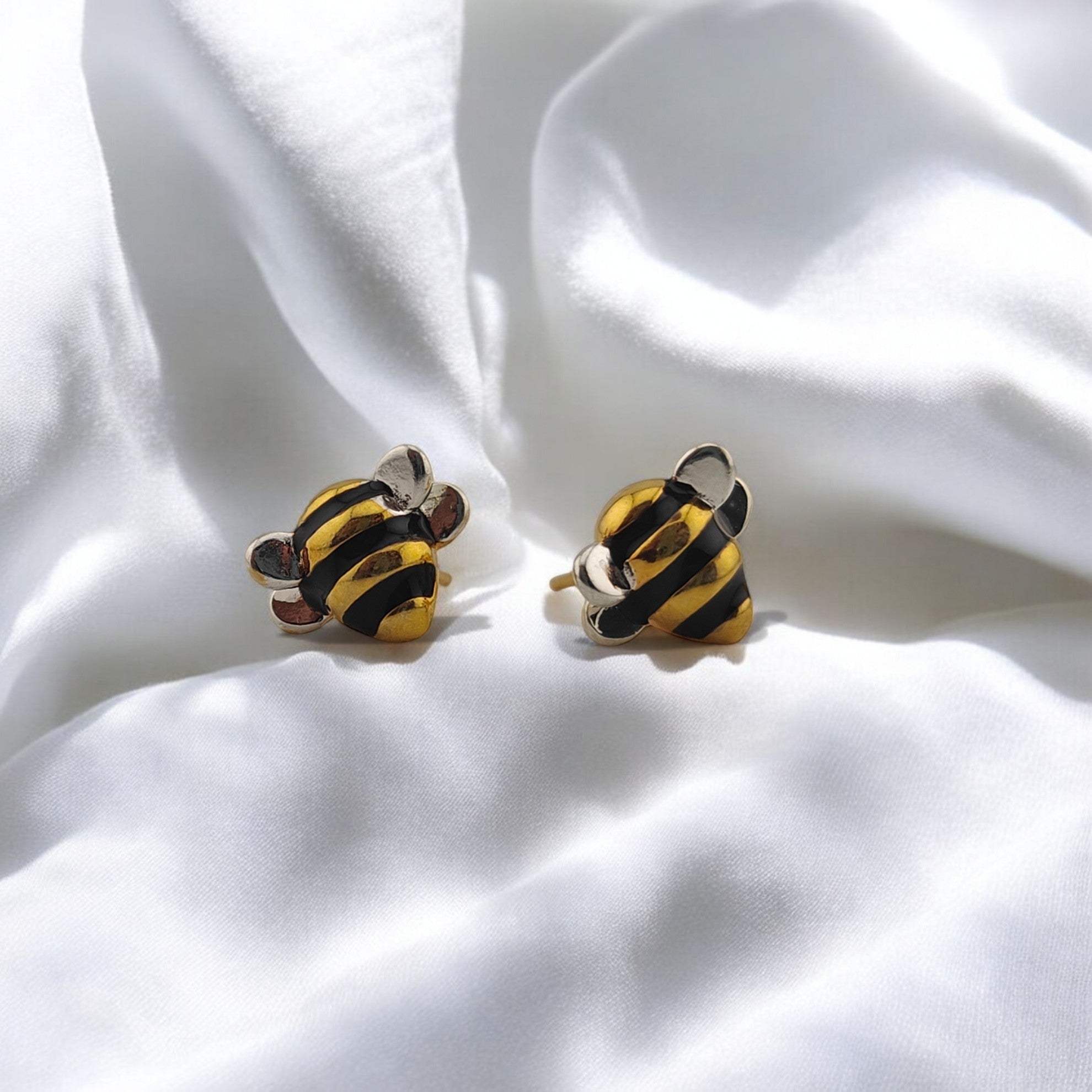 Close-up of enamel bee earrings in black and gold finish

