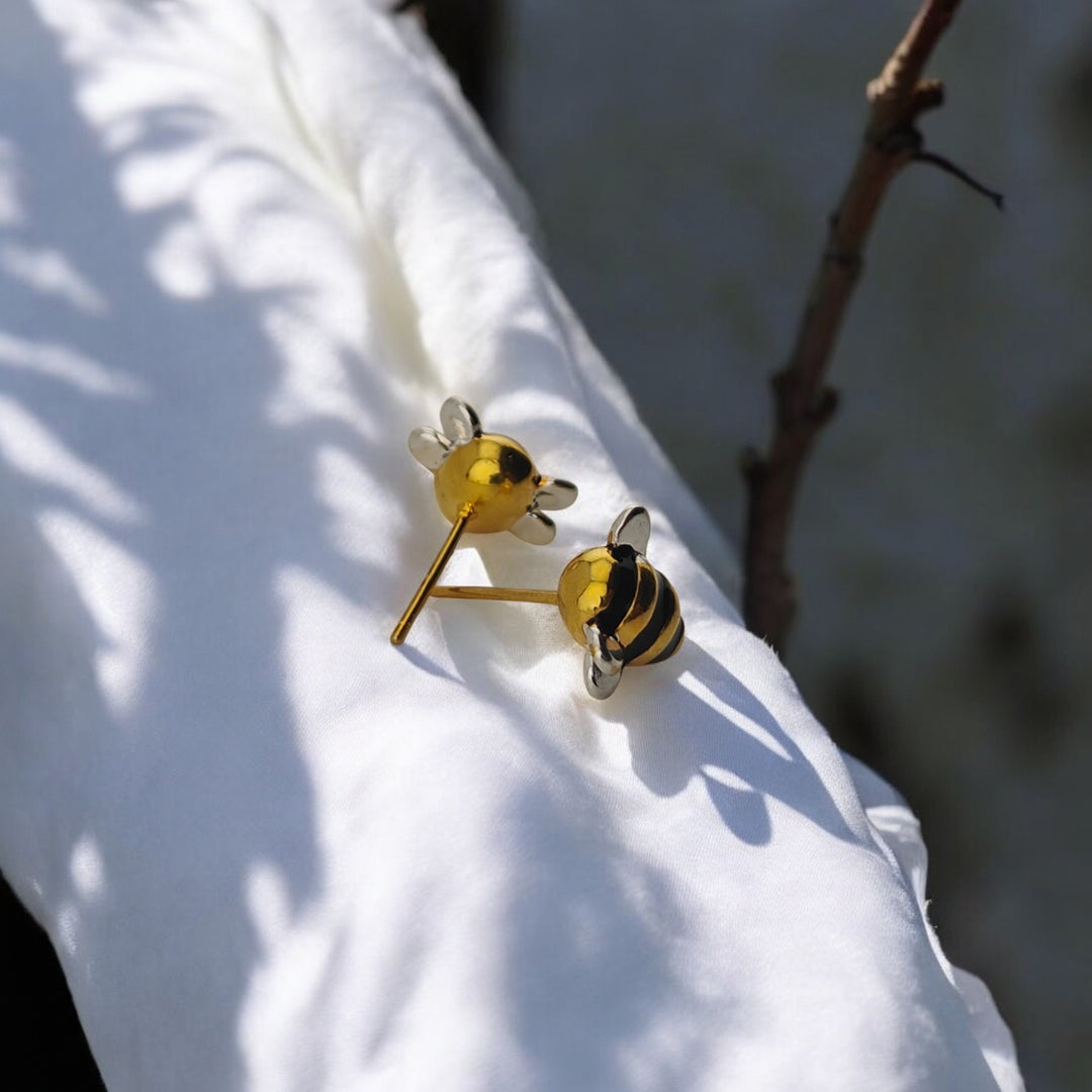  Pair of bee earrings displayed on cloth with natural shadows