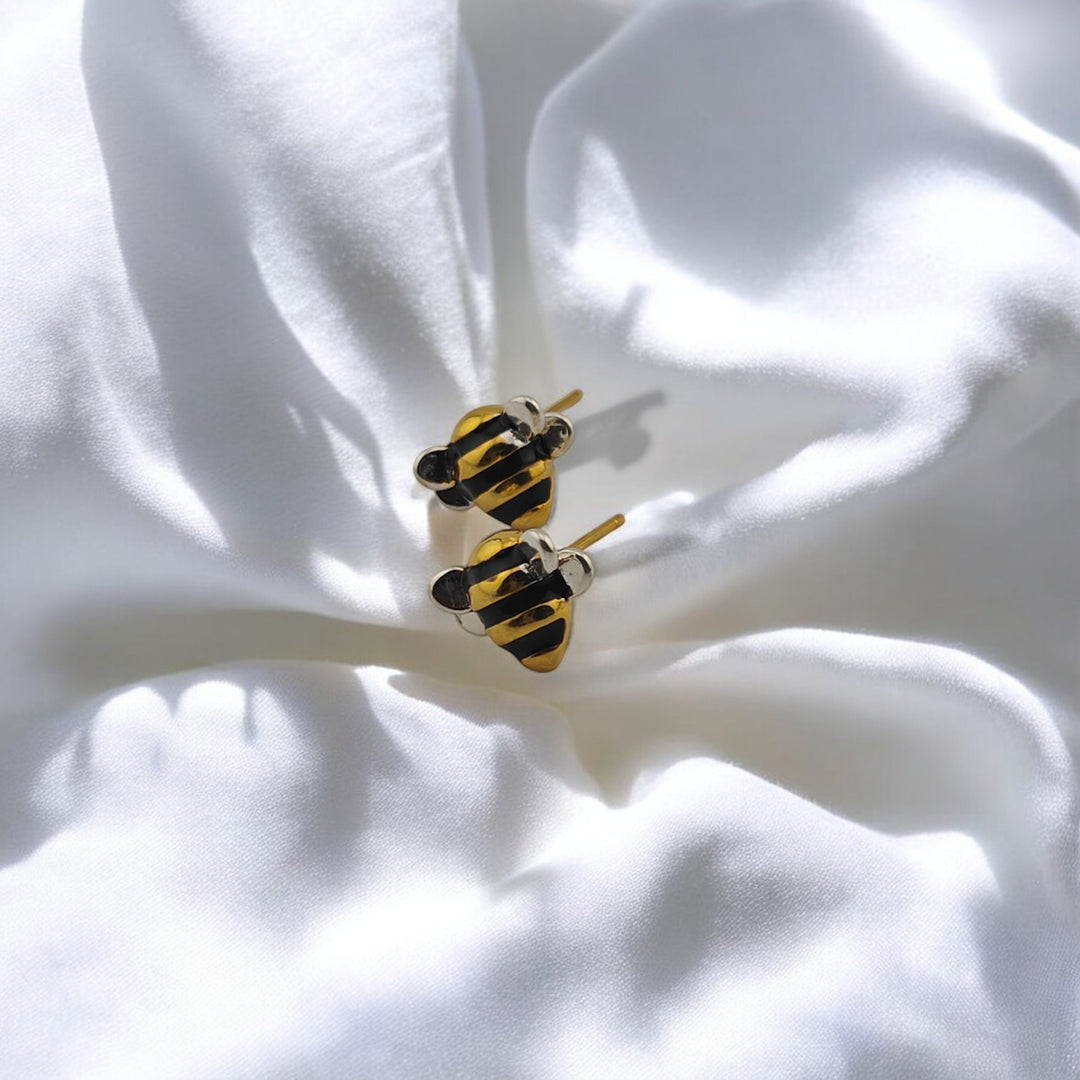Bee stud earrings on white satin with soft light