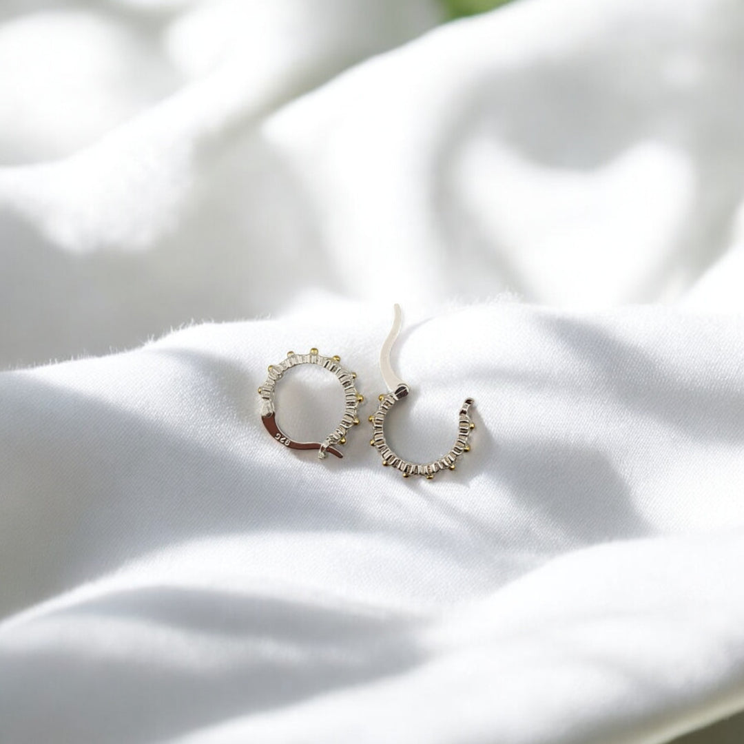 Floral hoop earrings with gold center details on white fabric background
