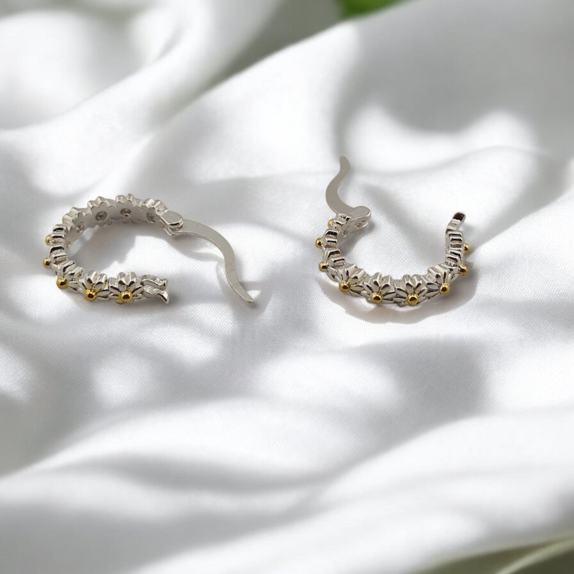 Nature-inspired hoop earrings with daisy pattern shown closed