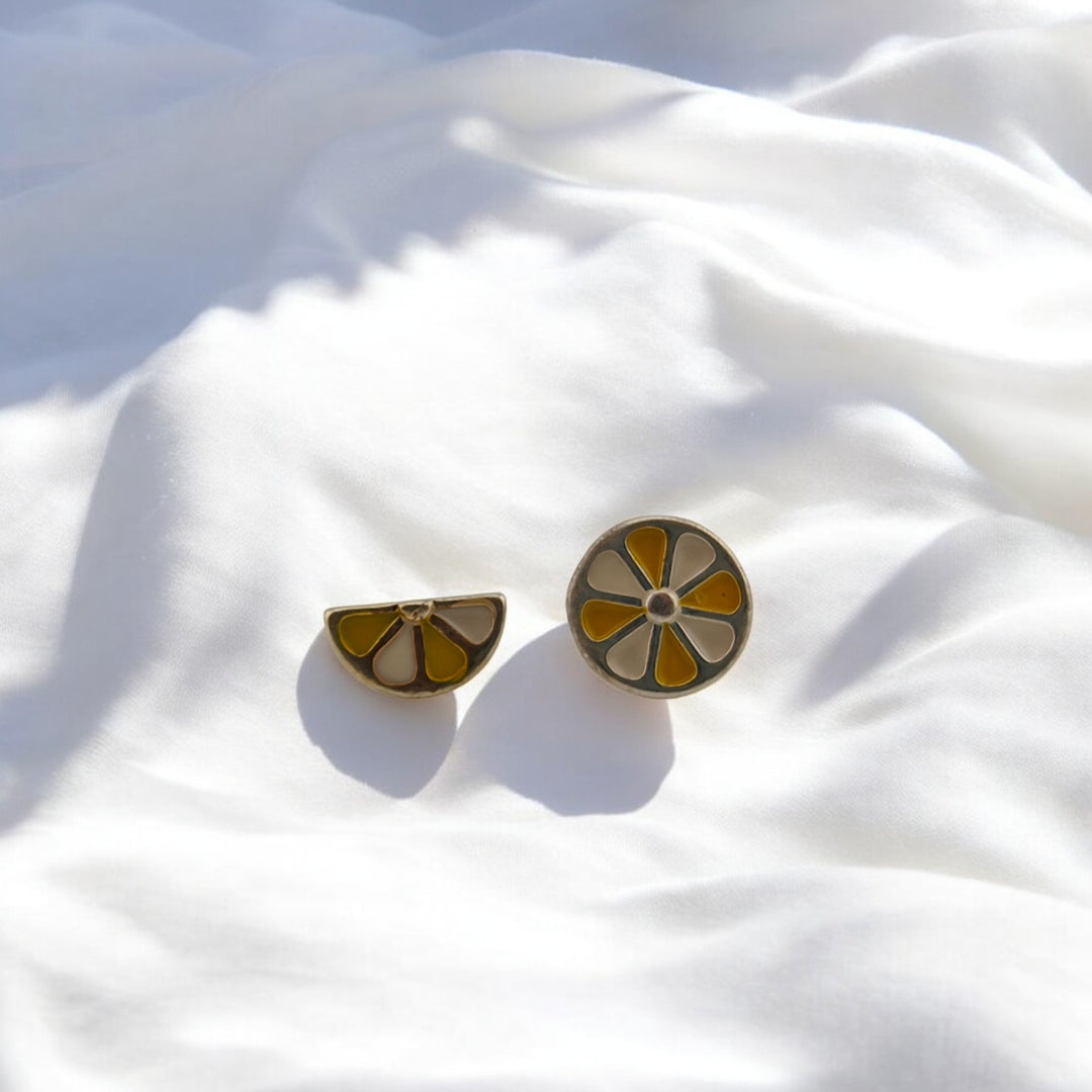 Close-up of a single round lemon slice stud earring on white silk
