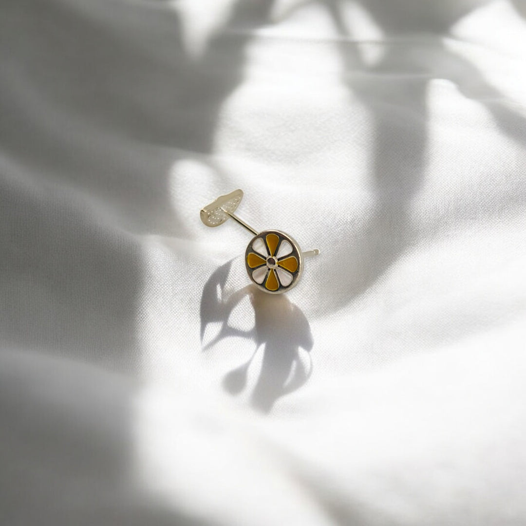  Round lemon stud earring lying flat on soft white fabric