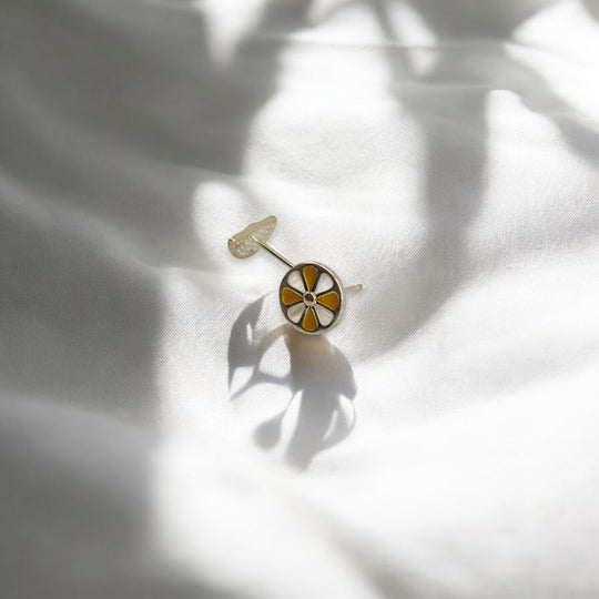  Round lemon stud earring lying flat on soft white fabric