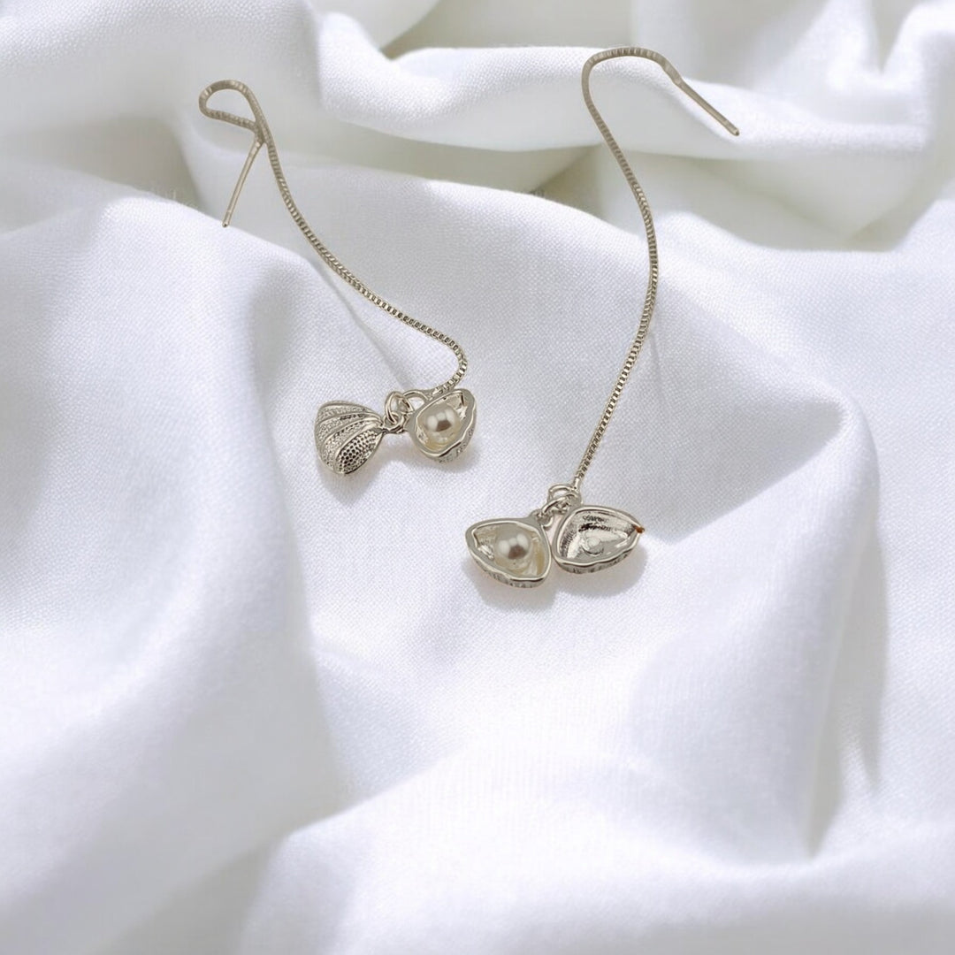Silver seashell threader earrings with pearl detail on soft white fabric