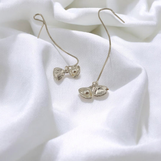 Silver seashell threader earrings with pearl detail on soft white fabric