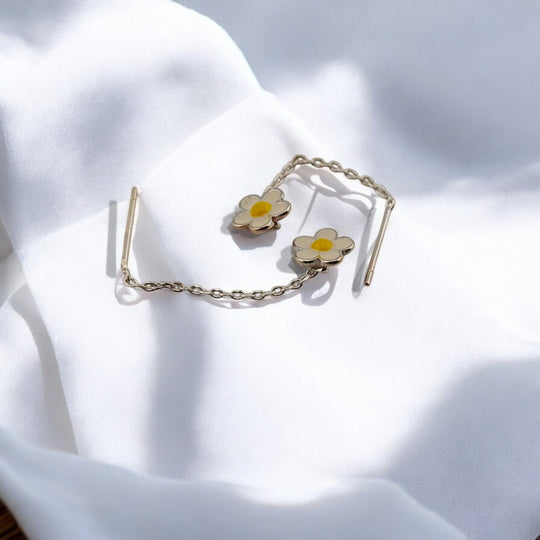 
Delicate threader earrings with daisy-shaped white and yellow flowers, photographed on white fabric in natural light.