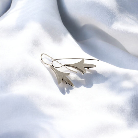 Floral earrings in silver with golden tips photographed in natural light