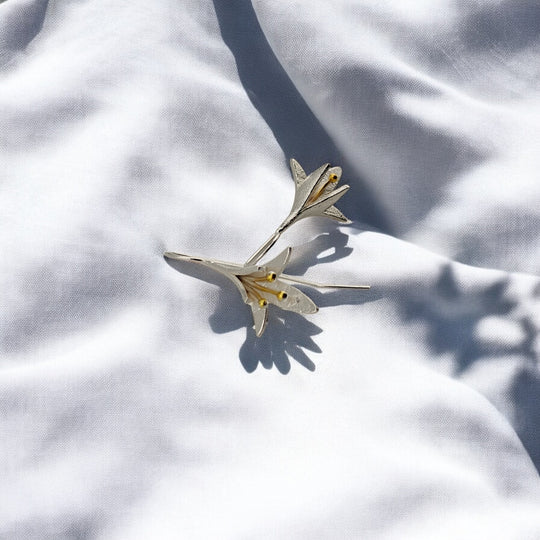 Silver lily-inspired earrings with long hook backs and soft shadows
