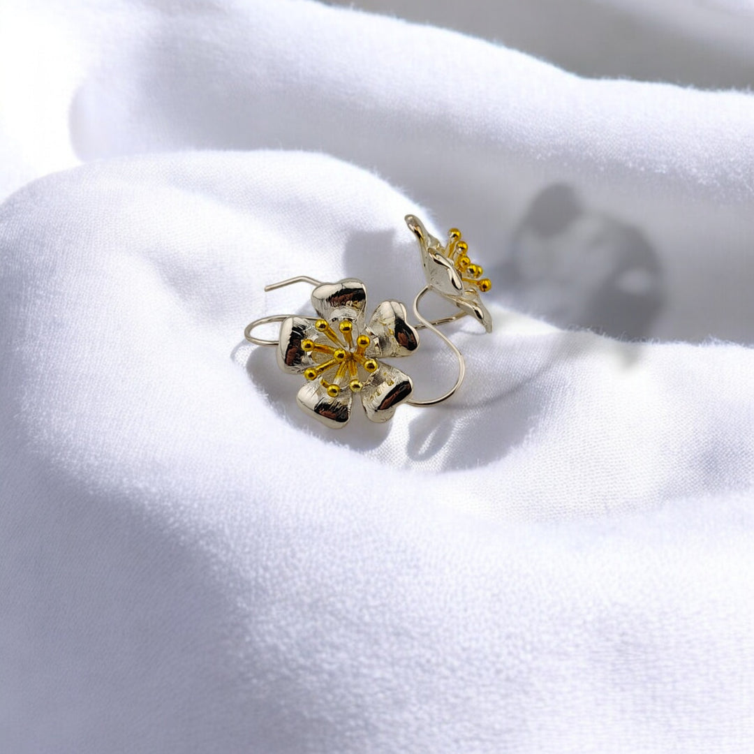 Angled view of floral earrings on white background, capturing shine and texture