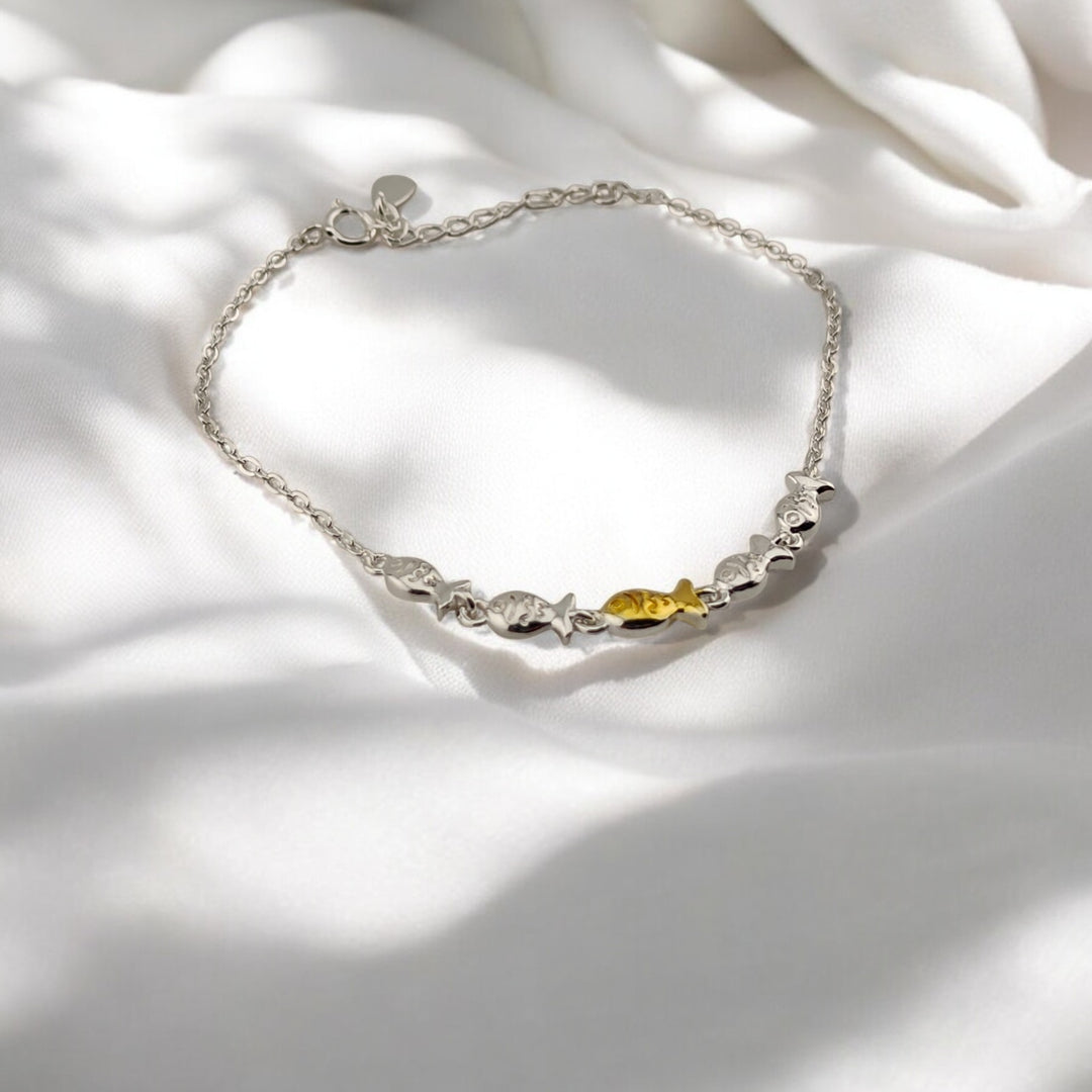 Side angle of silver bracelet showing gold fish centerpiece and adjustable chain

