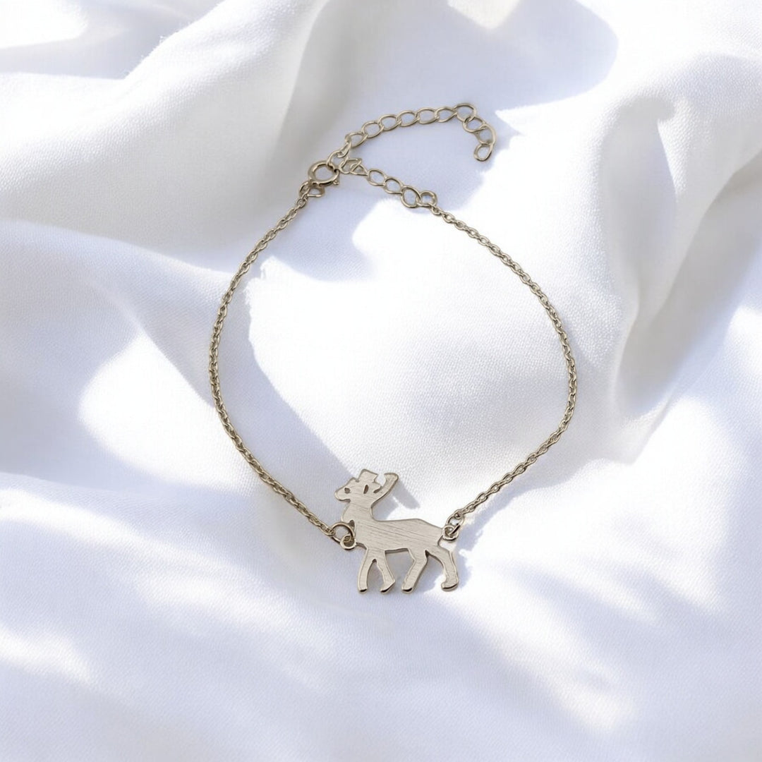 Minimalist photo of silver reindeer charm centered on a delicate bracelet, highlighted by daylight shadows.

