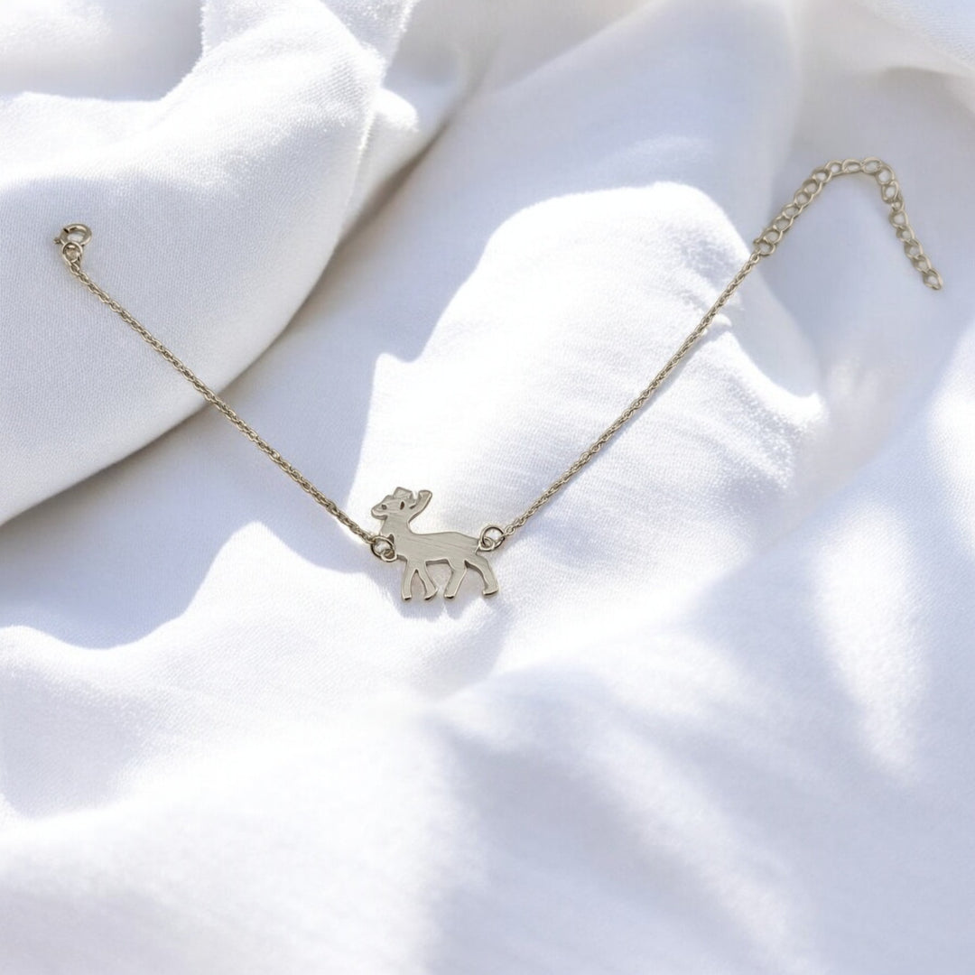 Full view of the RossJewelrys reindeer bracelet with extended chain laid out on white fabric background.


