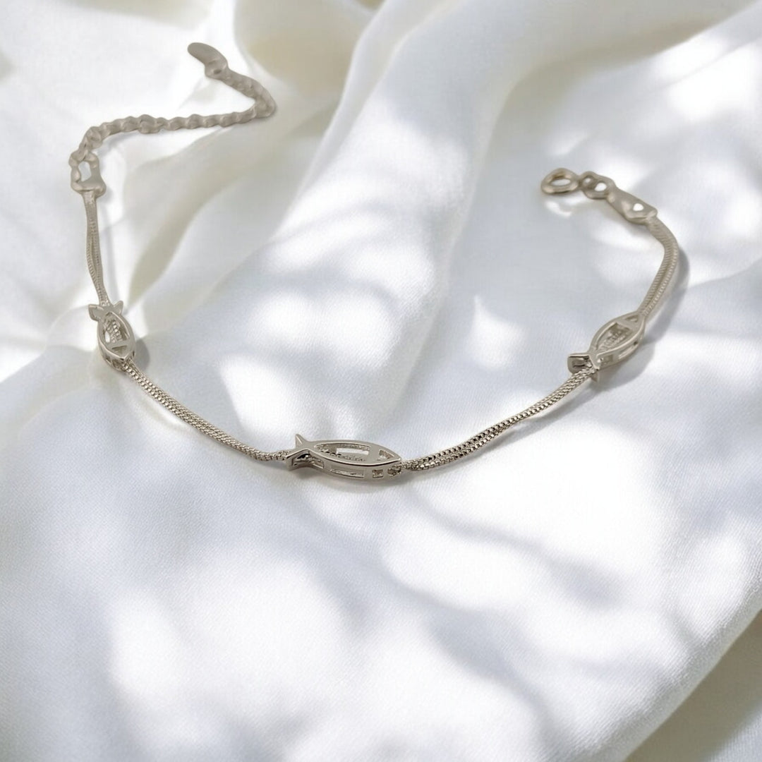 Detailed silver bracelet with clasp, featuring fish motif in natural light