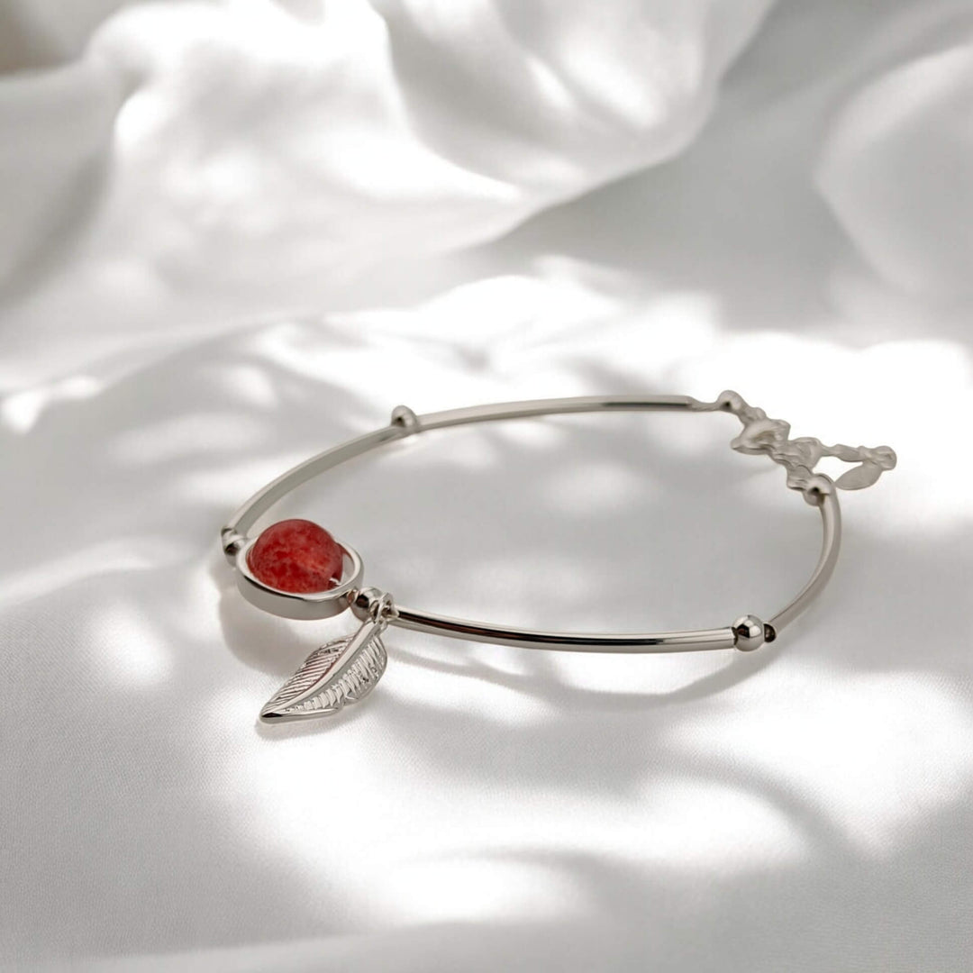 Side angle of delicate bracelet with red bead and silver feather