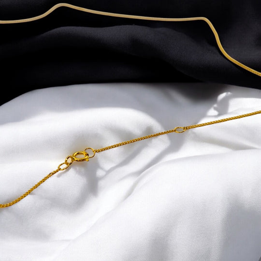 Close-up of 925 silver necklace with 18k gold plating on white and black fabric background – showcasing fine clasp design.

