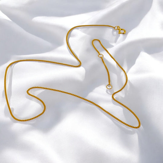 Minimalist box chain necklace in 18k gold-plated 925 silver with adjustable clasp, styled on soft white fabric – RossJewelrys product.

