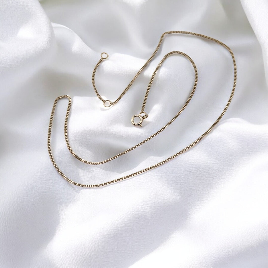 Sterling silver chain necklace fully extended over soft white fabric – modern box chain design from RossJewelrys.

