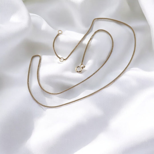 Sterling silver chain necklace fully extended over soft white fabric – modern box chain design from RossJewelrys.

