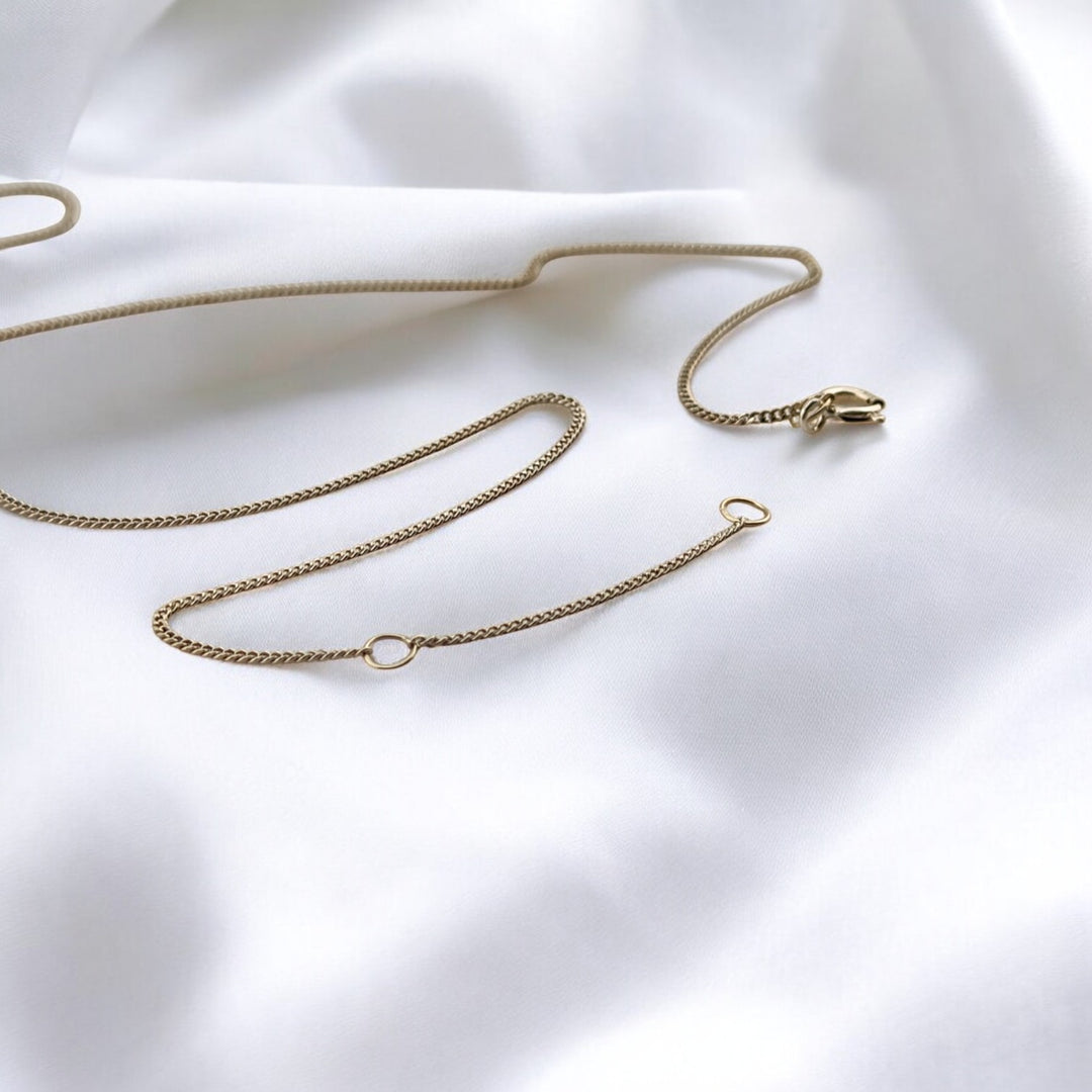 Silver chain necklace with adjustable clasp, laid in an abstract form – minimalist design photographed on white background.

