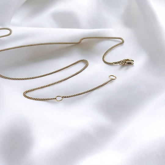Silver chain necklace with adjustable clasp, laid in an abstract form – minimalist design photographed on white background.

